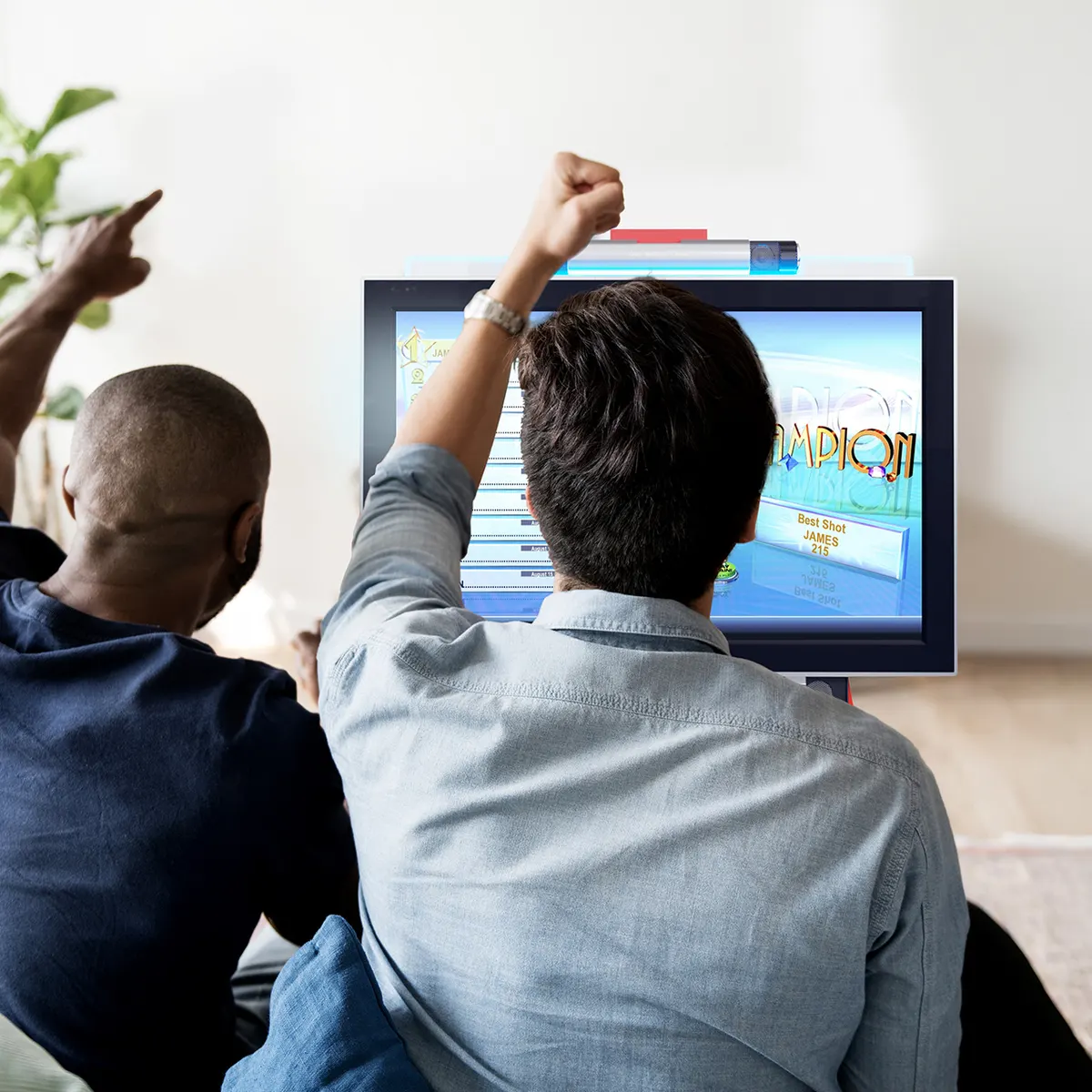 Two people celebrating in front of a JVL ECHO bartop arcade showing a leaderboard screen