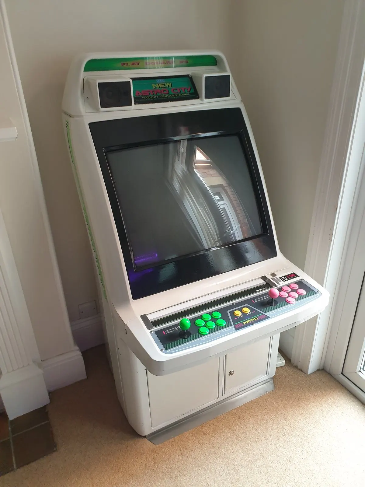 A white Sega New Astro City candy cabinet standing in a home hallway with its control panel and monitor visible