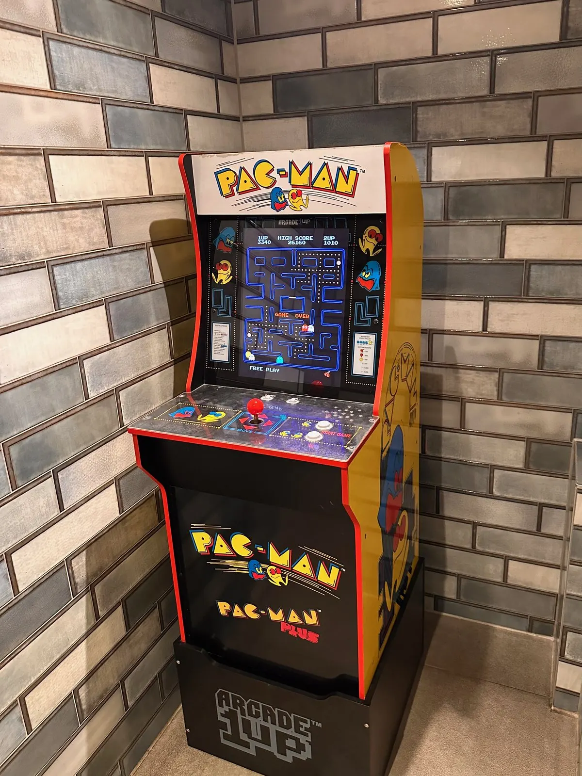 A three-quarter-scale replica arcade cabinet standing in the corner of a tiled cafe